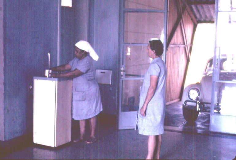 Corredor interno do sanatório de Lins, com funcionária junto a um bebedouro